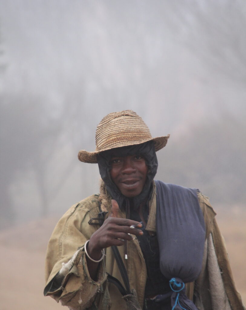 Antsirabe — smiling man wearing a straw hat in the fog
